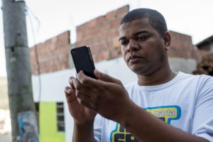 Favela tour guide Thiago Firmino takes a picture with his cell phone in Santa Marta shantytown in Rio de Janeiro, Brazil, on June 11, 2013. AFP PHOTO / YASUYOSHI CHIBA        (Photo credit should read YASUYOSHI CHIBA/AFP/Getty Images)