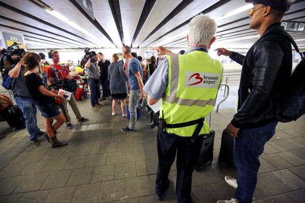 Members of the media stand next to an airport employee speaking with a man as passengers walk with luggage at Brussels' Zaventem airport on May 11, 2016, during a strike by employees of baggage handling company Aviapartner.  / AFP PHOTO / Belga / BRUNO FAHY / Belgium OUT strike aviation Horizontal