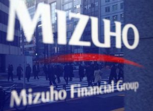 Pedestrians are reflected on Mizuho Bank's signboard in Tokyo, Japan, January 25, 2017. Picture taken January 25, 2017.  REUTERS/Kim Kyung-Hoon